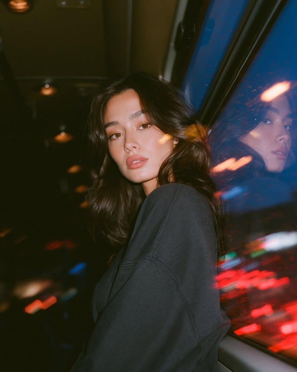 Photorealistic cinematic portrait of a young woman sitting inside a moving