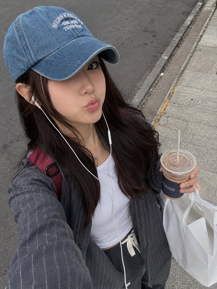 Photorealistic candid street-style selfie of a young woman walking outdoors on
